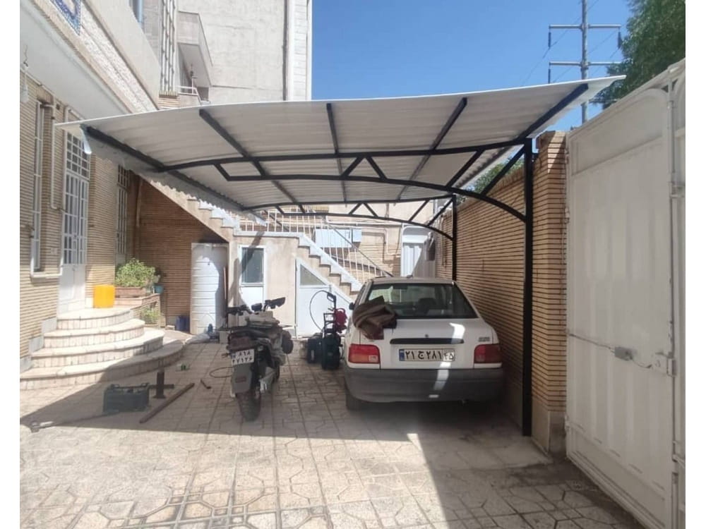خودروی پارکشده زیر سایبان ثابت با سقف روشن در حیاط ساختمان در کرمان