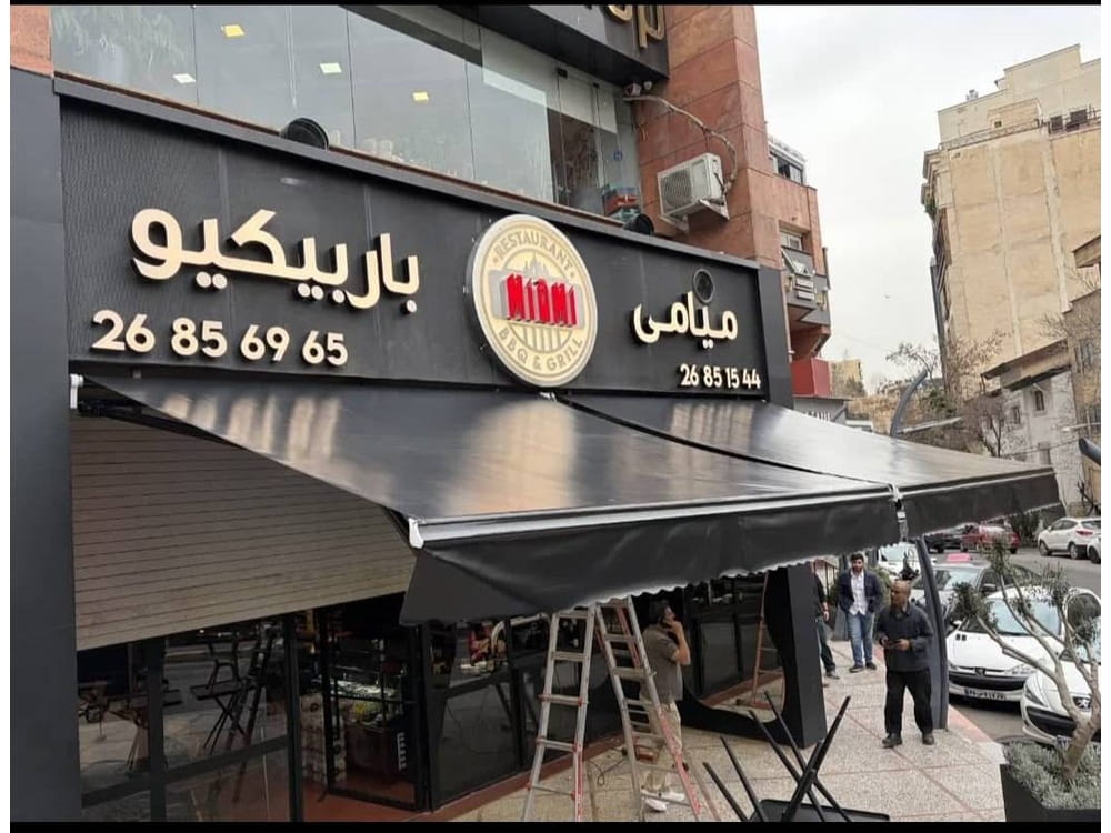 دو سایبان بازویی مشکی کنار هم در نمای کافه میامی باربیکیو تهران
