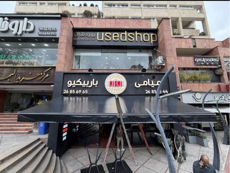 نمای نزدیک سایبان بازویی مشکی و آویز جلویی کافه میامی باربیکیو در تهران
