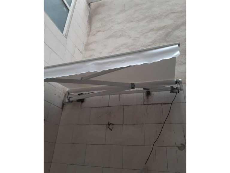 سایبان بازویی سفید با آویز دالبر نصب‌شده در تراس تهرانپارس